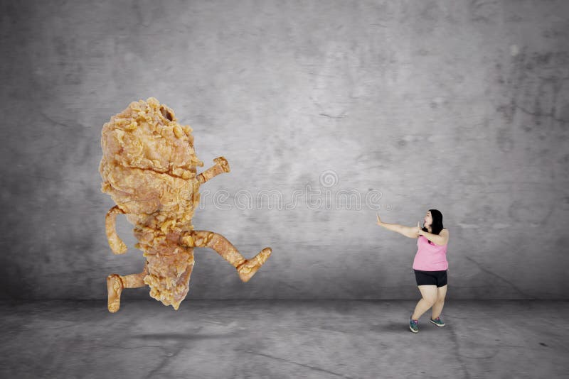 Donna di peso eccessivo che sfugge da un pollo fritto fotografia stock Donna di peso eccessivo che sfugge da un pollo fritto fotografia stock
