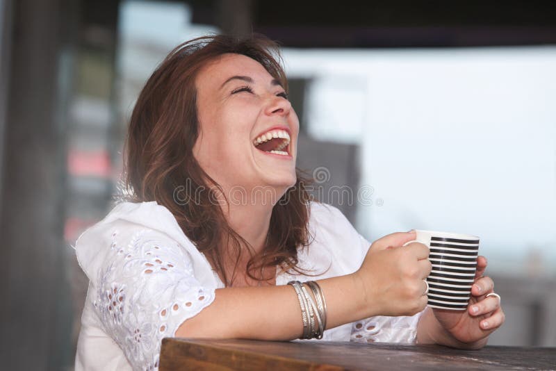 Donna di risata con una tazza della bevanda