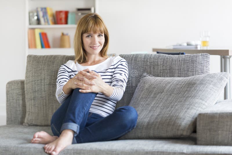 Donna di trenta anni naturale messa sullo strato nella casa moderna fotografia stock libera da diritti Donna di trenta anni naturale messa sullo strato nella casa moderna fotografia stock libera da diritti