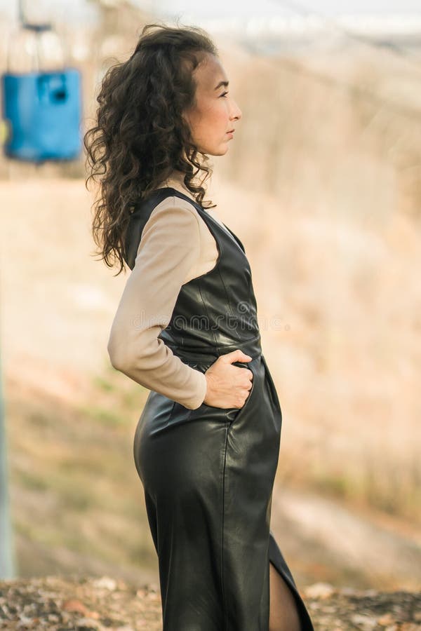 Donna di vista laterale nel parcheggio in caduta sullo sfondo della funivia. donna con capelli ricci lunghi. bella luce del sole fotografie stock libere da diritti