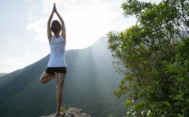 Donna di yoga che medita su bordo della scogliera del picco di montagna fotografie stock Donna di yoga che medita su bordo della scogliera del picco di montagna fotografie stock