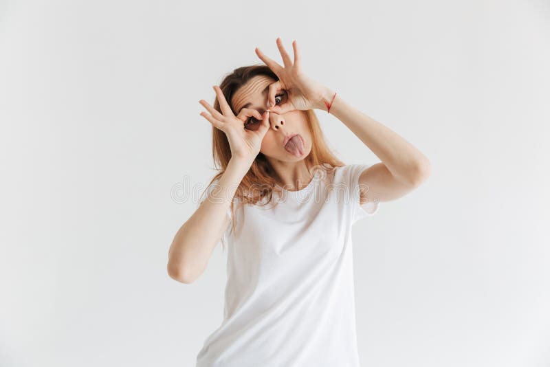 Donna divertente in armi della tenuta della maglietta sugli occhi come la maschera fotografia stock libera da diritti Donna divertente in armi della tenuta della maglietta sugli occhi come la maschera fotografia stock libera da diritti