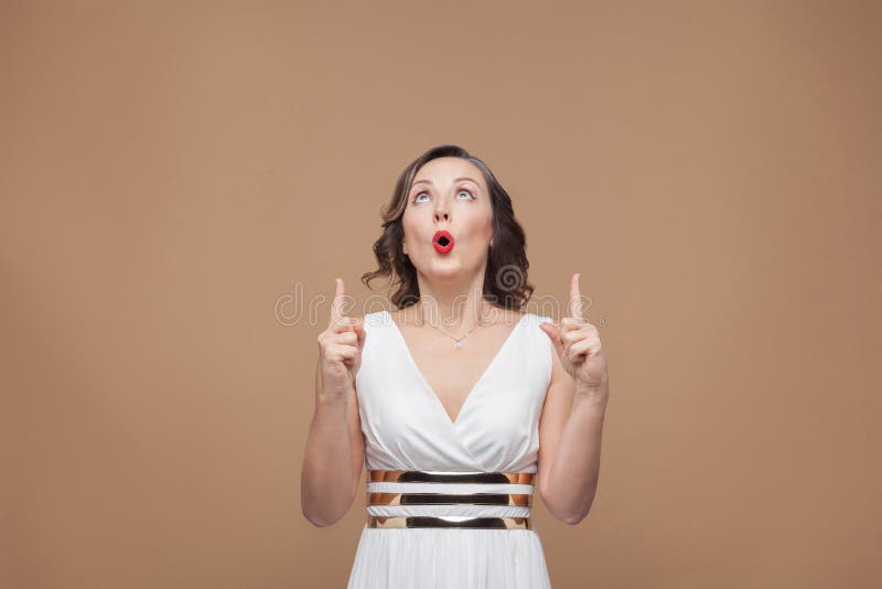 Donna domandata che indica dito su allo spazio della copia immagini stock Donna domandata che indica dito su allo spazio della copia immagini stock