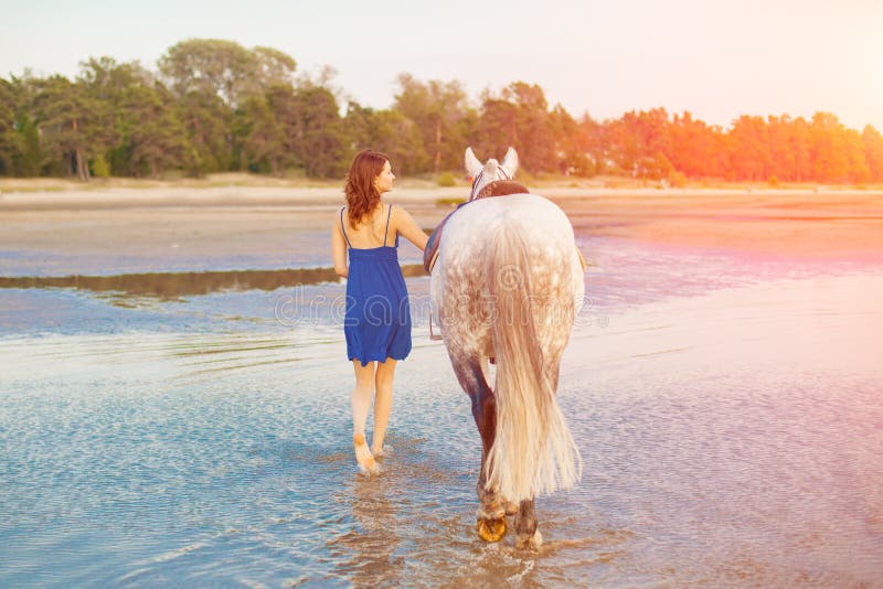 Donna e cavallo sui precedenti del cielo e dell'acqua Ragazza o di modello fotografia stock Donna e cavallo sui precedenti del cielo e dell'acqua Ragazza o di modello fotografia stock