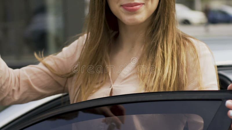 Donna felice che compra nuova automobile, mostrante le chiavi alla macchina fotografica, riuscita donna di affari