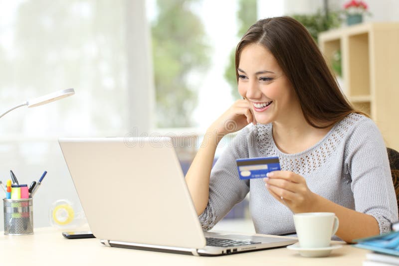 Donna felice che paga con la carta di credito sul portatile fotografia stock
