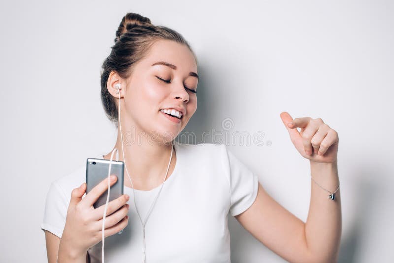 Donna felice che per mezzo del telefono cellulare mentre ascoltando la musica sullo smartphone, immagini stock libere da diritti Donna felice che per mezzo del telefono cellulare mentre ascoltando la musica sullo smartphone, immagini stock libere da diritti