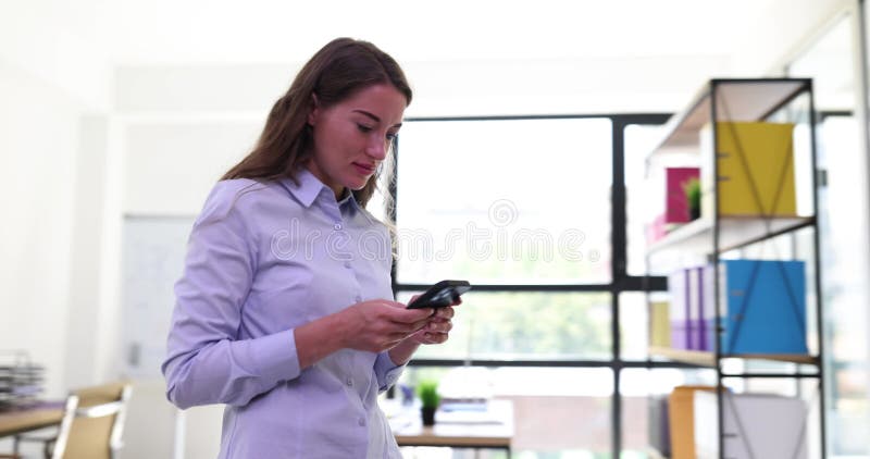 Donna felice che usa app di navigazione telefonica e cammina per l'ufficio