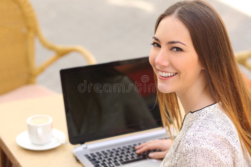 Donna felice che utilizza un computer portatile in un ristorante ed esaminando macchina fotografica immagine stock libera da diritti