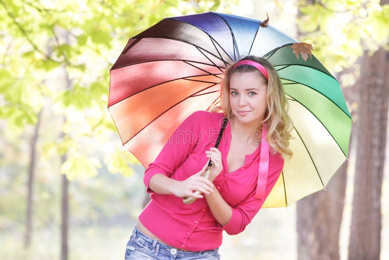 Donna felice con l'ombrello variopinto nel parco di autunno