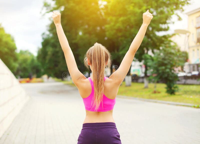 Donna felice del corridore di forma fisica che gode dopo la formazione nel parco della città, nel vincitore del corridore, nelle immagine stock libera da diritti Donna felice del corridore di forma fisica che gode dopo la formazione nel parco della città, nel vincitore del corridore, nelle immagine stock libera da diritti