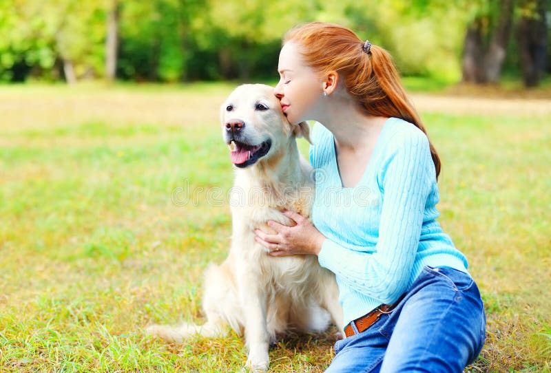 Donna felice del proprietario che bacia il cane di golden retriever fotografia stock libera da diritti Donna felice del proprietario che bacia il cane di golden retriever fotografia stock libera da diritti