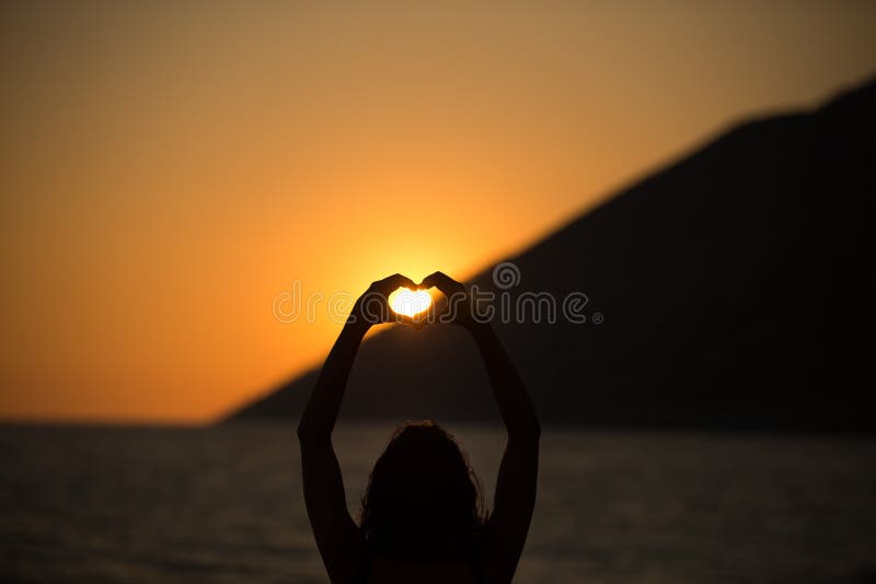 Donna felice libera che gode del tramonto Abbracciando l'incandescenza del sole del tramonto dorata, godente della pace, serenità fotografia stock libera da diritti