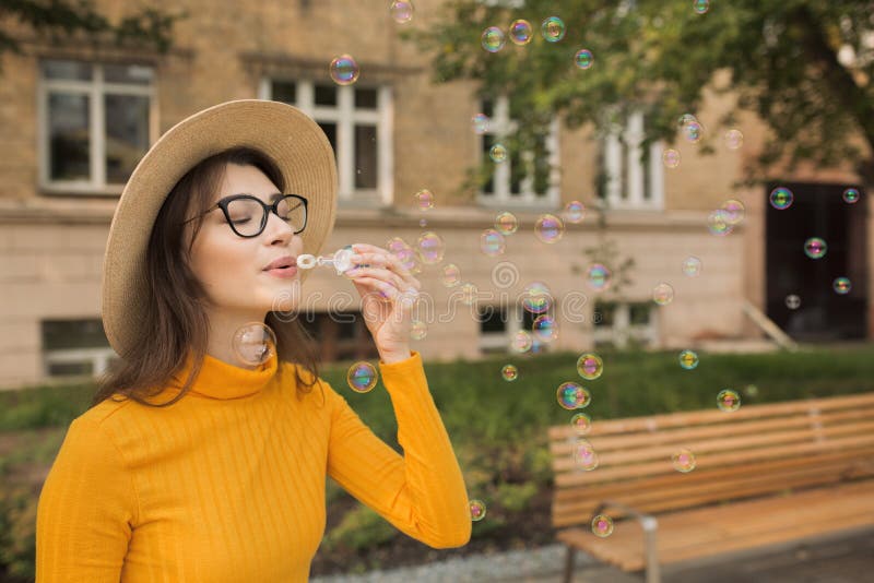 Donna felice nelle bolle di sapone di salto della città fotografie stock libere da diritti Donna felice nelle bolle di sapone di salto della città fotografie stock libere da diritti