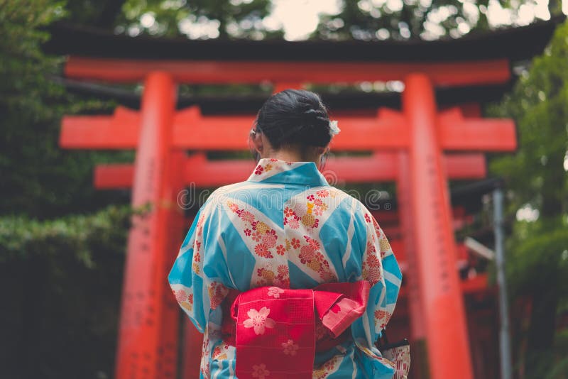 Donna giapponese in kimono davanti ad un tunnel di Torii immagine stock libera da diritti Donna giapponese in kimono davanti ad un tunnel di Torii immagine stock libera da diritti