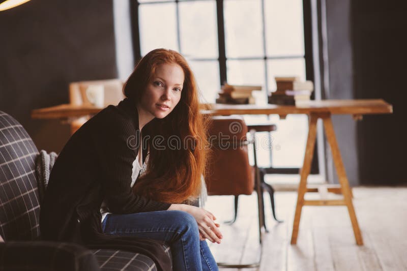 donna giovane del readhead che si rilassa a casa sullo strato accogliente, vestito in maglione e jeans casuali fotografia stock donna giovane del readhead che si rilassa a casa sullo strato accogliente, vestito in maglione e jeans casuali fotografia stock