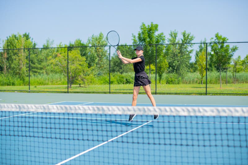 Donna giovane di sport che gioca a tennis sul campo da tennis blu fotografia stock Donna giovane di sport che gioca a tennis sul campo da tennis blu fotografia stock
