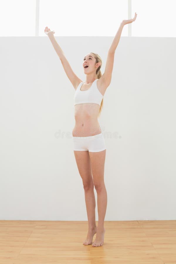 Donna giuliva di misura in abiti sportivi che allungano alzandola armi immagine stock Donna giuliva di misura in abiti sportivi che allungano alzandola armi immagine stock