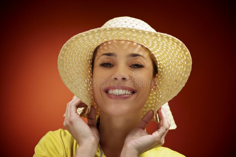 Donna graziosa con il cappello di paglia che sorride alla macchina fotografica immagine stock libera da diritti Donna graziosa con il cappello di paglia che sorride alla macchina fotografica immagine stock libera da diritti