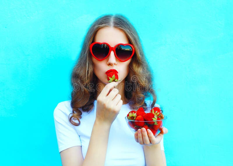 Donna graziosa del ritratto con i molti fragola sopra il blu variopinto immagini stock