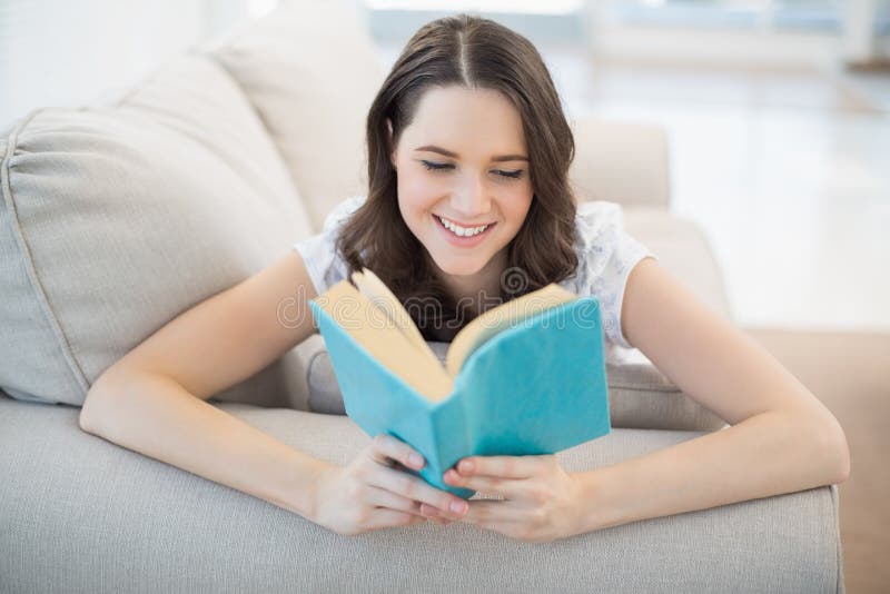 Donna graziosa pacifica che si trova su un libro di lettura accogliente dello strato immagini stock libere da diritti Donna graziosa pacifica che si trova su un libro di lettura accogliente dello strato immagini stock libere da diritti