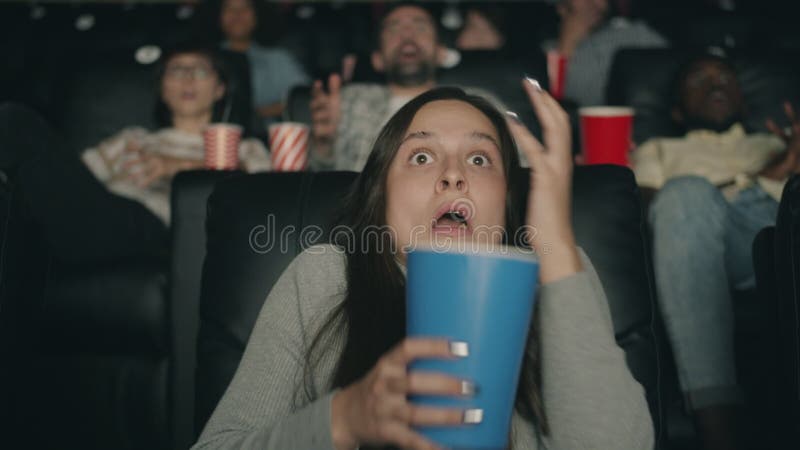 Donna impaurita che guarda film spaventoso al cinema mangiando popcorn occhi chiusi