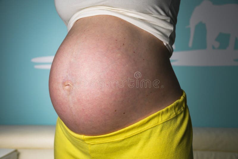 Donna incinta a casa che mostra la sua bella, pancia piacevolmente arrotondata fotografie stock libere da diritti Donna incinta a casa che mostra la sua bella, pancia piacevolmente arrotondata fotografie stock libere da diritti