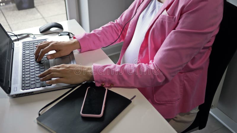 Donna incinta che lavora al computer in ufficio.