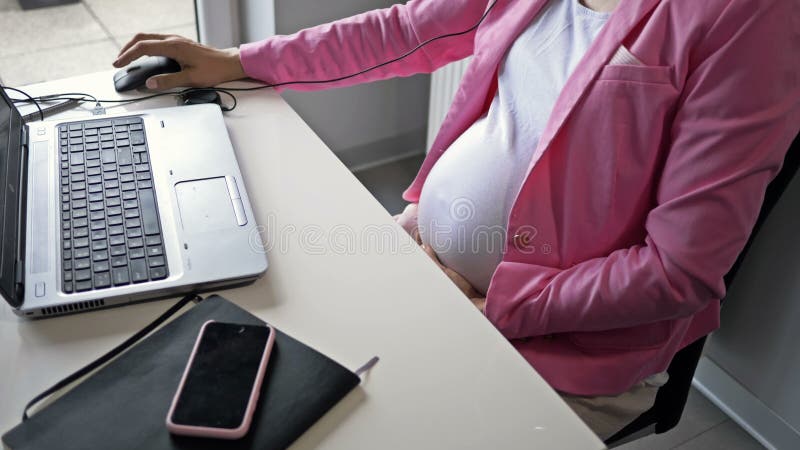 Donna incinta che lavora al computer in ufficio.