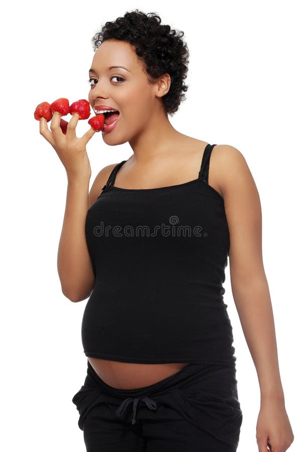 Donna incinta che mangia le fragole fotografia stock Donna incinta che mangia le fragole fotografia stock