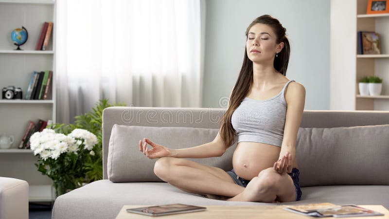 Donna incinta che medita nella posizione di loto, casa di pratica di yoga per rilassamento fotografie stock libere da diritti Donna incinta che medita nella posizione di loto, casa di pratica di yoga per rilassamento fotografie stock libere da diritti