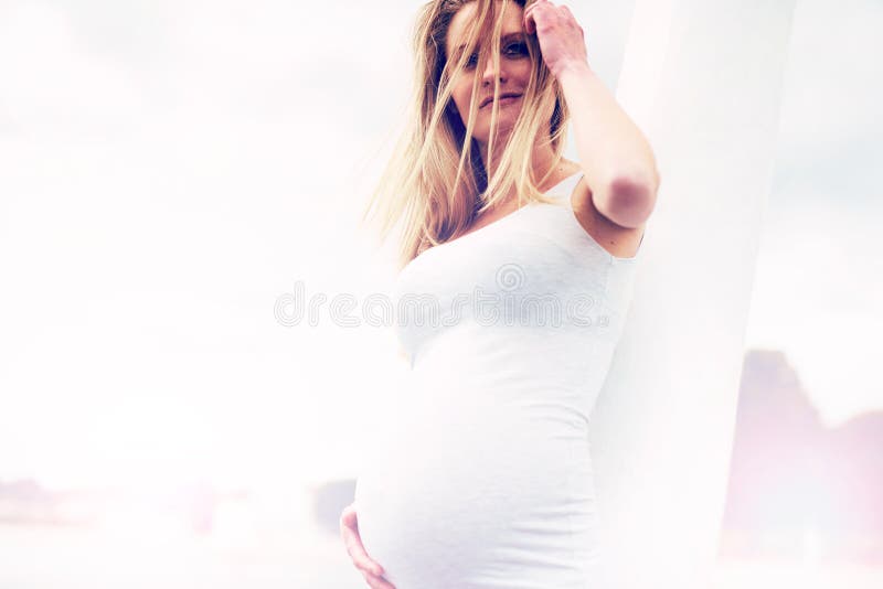 Donna incinta che pende contro una colonna fotografie stock libere da diritti Donna incinta che pende contro una colonna fotografie stock libere da diritti