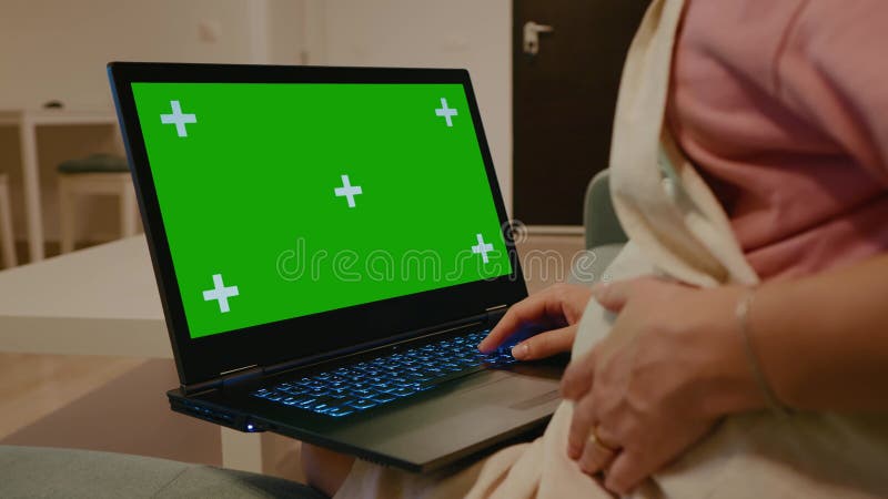 Donna incinta che scrive sul computer chroma key portatile al chiuso. video d archivio
