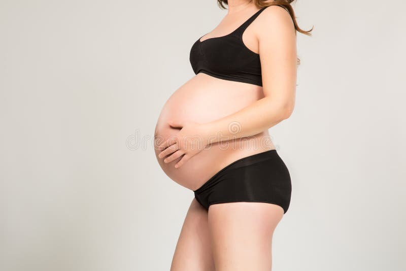 Donna incinta nel colpo nero dello studio della biancheria intima immagine stock