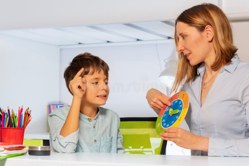 Boy with autism spectrum disorder learn clock and hours, teacher during ABA therapy class. Boy with autism spectrum disorder learn clock and hours, teacher during ABA therapy class