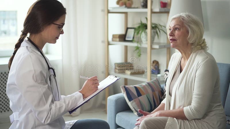 Donna invecchiata che parla con il professionista nella sua casa