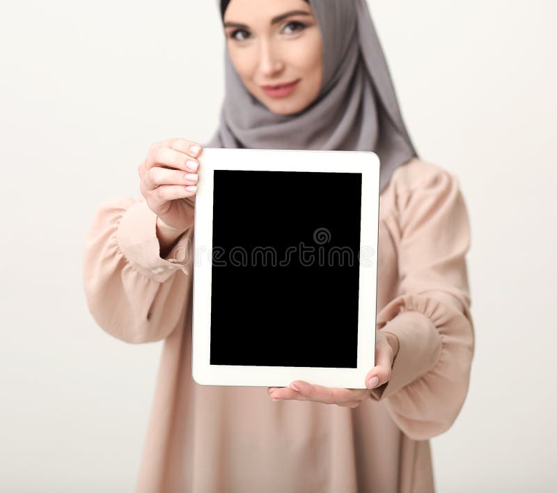 Donna islamica che mostra compressa con lo schermo in bianco immagine stock Donna islamica che mostra compressa con lo schermo in bianco immagine stock