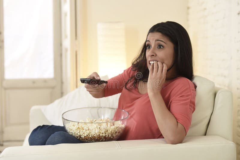 Donna latina che si siede a casa lo strato del sofà nel film horror spaventoso di sorveglianza della televisione del salone
