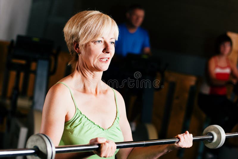 Donna maggiore con il barbell in ginnastica