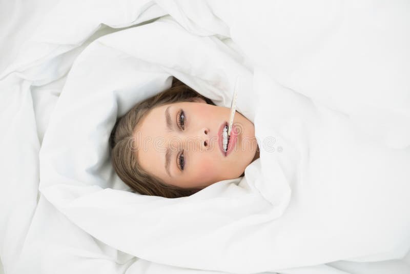 Donna malata che si trova nell'ambito della copertura sul suo letto nella camera da letto fotografia stock libera da diritti Donna malata che si trova nell'ambito della copertura sul suo letto nella camera da letto fotografia stock libera da diritti