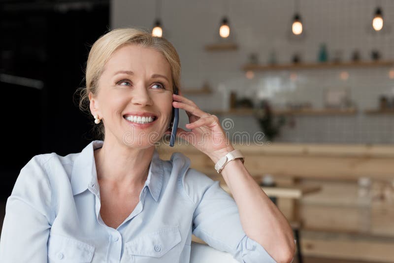 donna matura allegra che parla sullo smartphone e sul distogliere lo sguardo fotografia stock libera da diritti donna matura allegra che parla sullo smartphone e sul distogliere lo sguardo fotografia stock libera da diritti