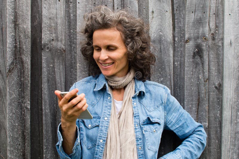 Donna matura che sorride con il telefono fotografia stock Donna matura che sorride con il telefono fotografia stock