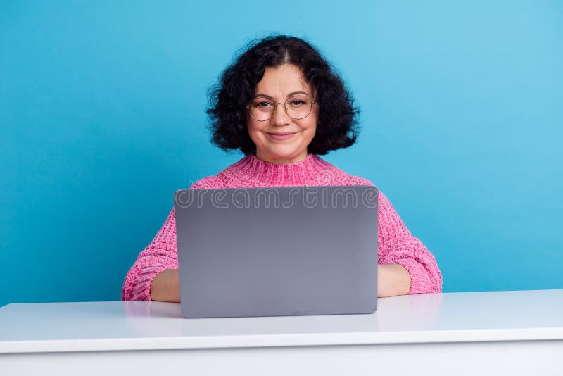 Donna matura lavora sul suo netbook isolata su sfondo di colore blu fotografie stock libere da diritti