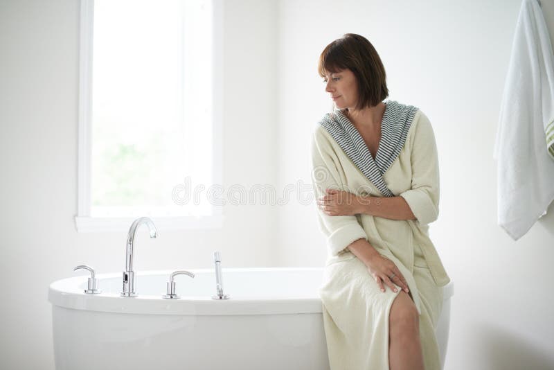 Donna matura serena che si siede da una vasca immagine stock libera da diritti Donna matura serena che si siede da una vasca immagine stock libera da diritti