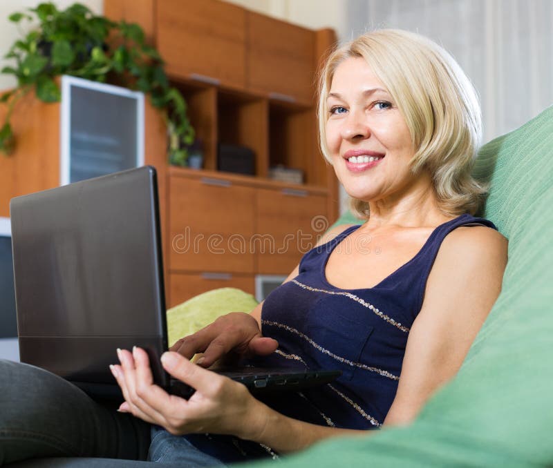 Donna matura sorridente che per mezzo del computer portatile fotografia stock libera da diritti Donna matura sorridente che per mezzo del computer portatile fotografia stock libera da diritti