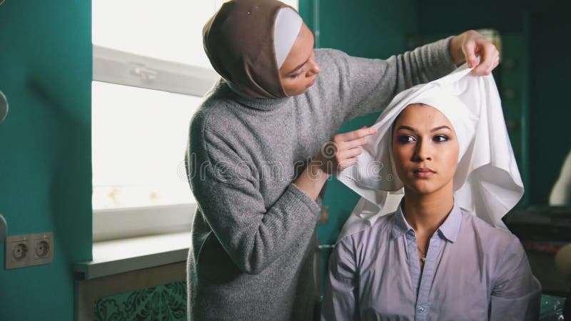 Donna musulmana che crea l'abbigliamento tradizionale islamico di nozze per la bella sposa fotografia stock libera da diritti Donna musulmana che crea l'abbigliamento tradizionale islamico di nozze per la bella sposa fotografia stock libera da diritti
