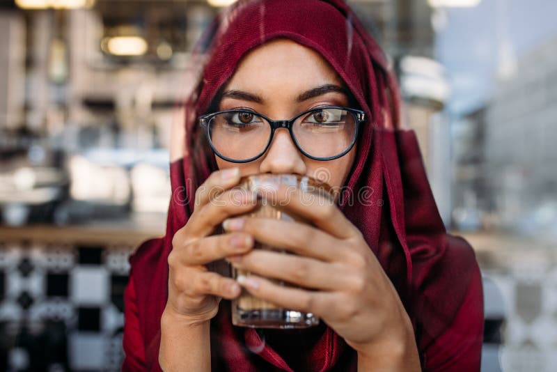Donna musulmana che mangia caffè al caffè immagini stock Donna musulmana che mangia caffè al caffè immagini stock