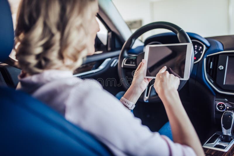 Donna nell'automobile facendo uso della compressa digitale fotografia stock Donna nell'automobile facendo uso della compressa digitale fotografia stock