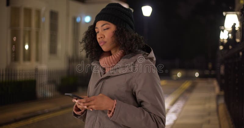 Donna nera che rimuove i guanti per usare l'app smartphone rideshare per chiamare un passaggio