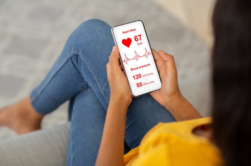 Young black lady chilling at home, using health app on smartphone while sitting on couch. Closeup of mobile phone with heart rate inscription on screen in unrecognizable african american woman hands. Young black lady chilling at home, using health app on smartphone while sitting on couch. Closeup of mobile phone with heart rate inscription on screen in unrecognizable african american woman hands